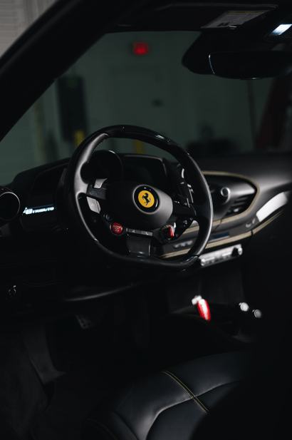 Interior view of the 2020 Ferrari F8 Tributo showcasing the steering wheel and luxury design.