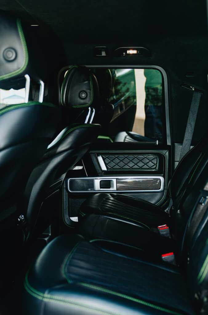 Interior view of the luxurious seating in the 2022 Mercedes G63 AMG (Brabus Kit), featuring black leather and green accents.
