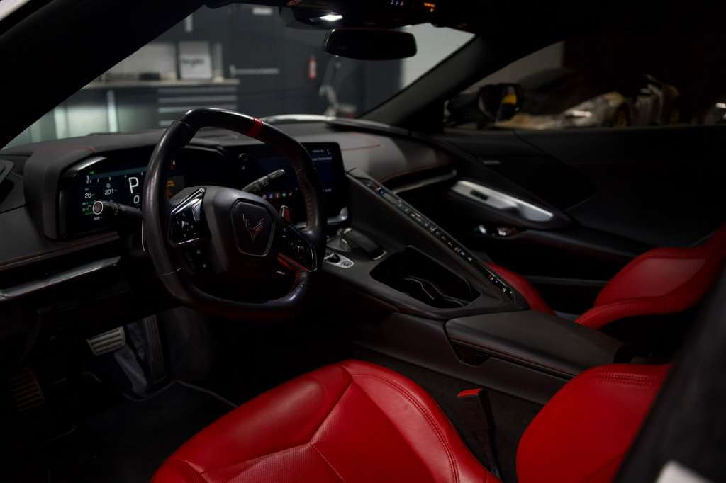 Interior of the 2023 Corvette C8 featuring red leather seats and advanced tech dashboard.