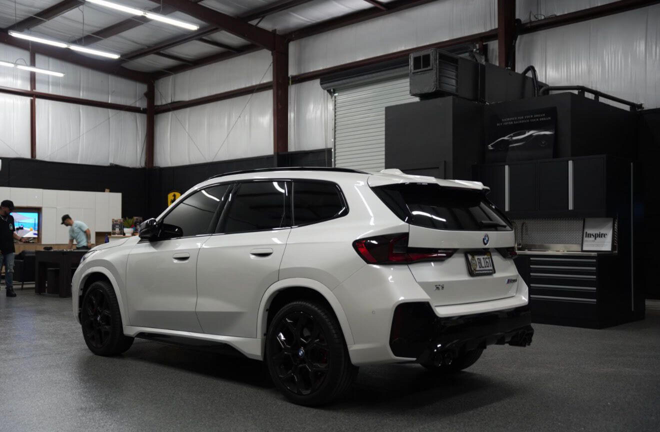2024 BMW X1 M35i rear view in a sleek automotive workshop, showcasing its luxurious design and features.