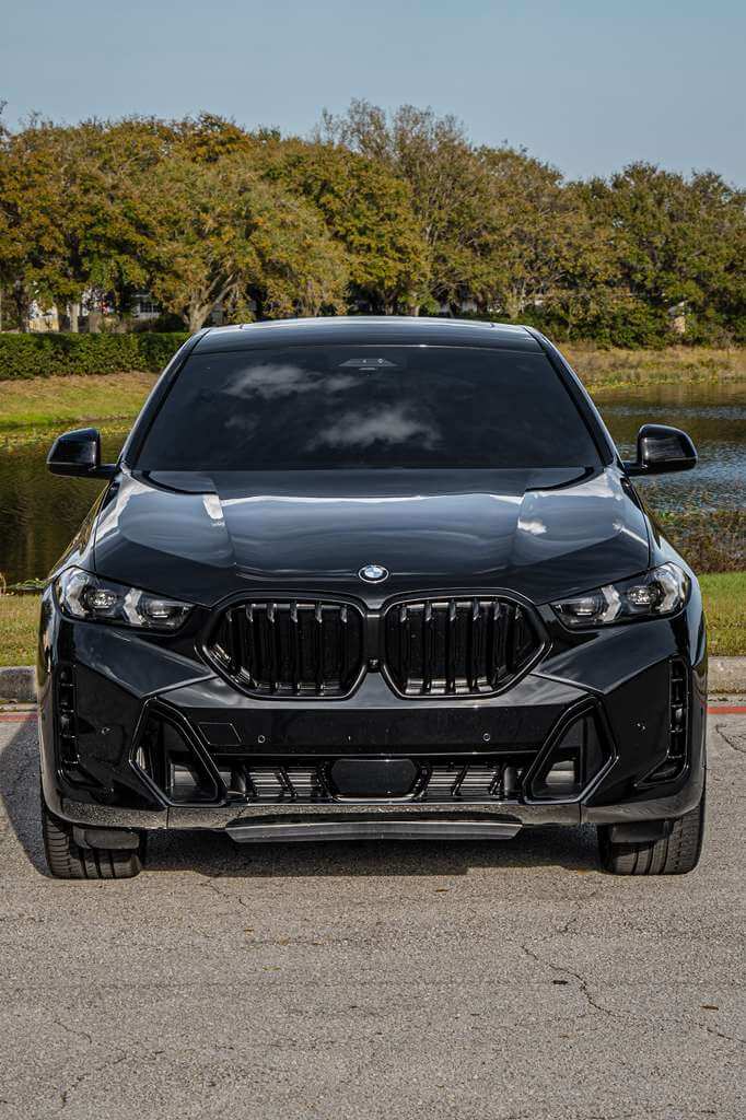 2026 BMW X6 black luxury SUV parked by a lake in Orlando, showcasing its bold design and performance.