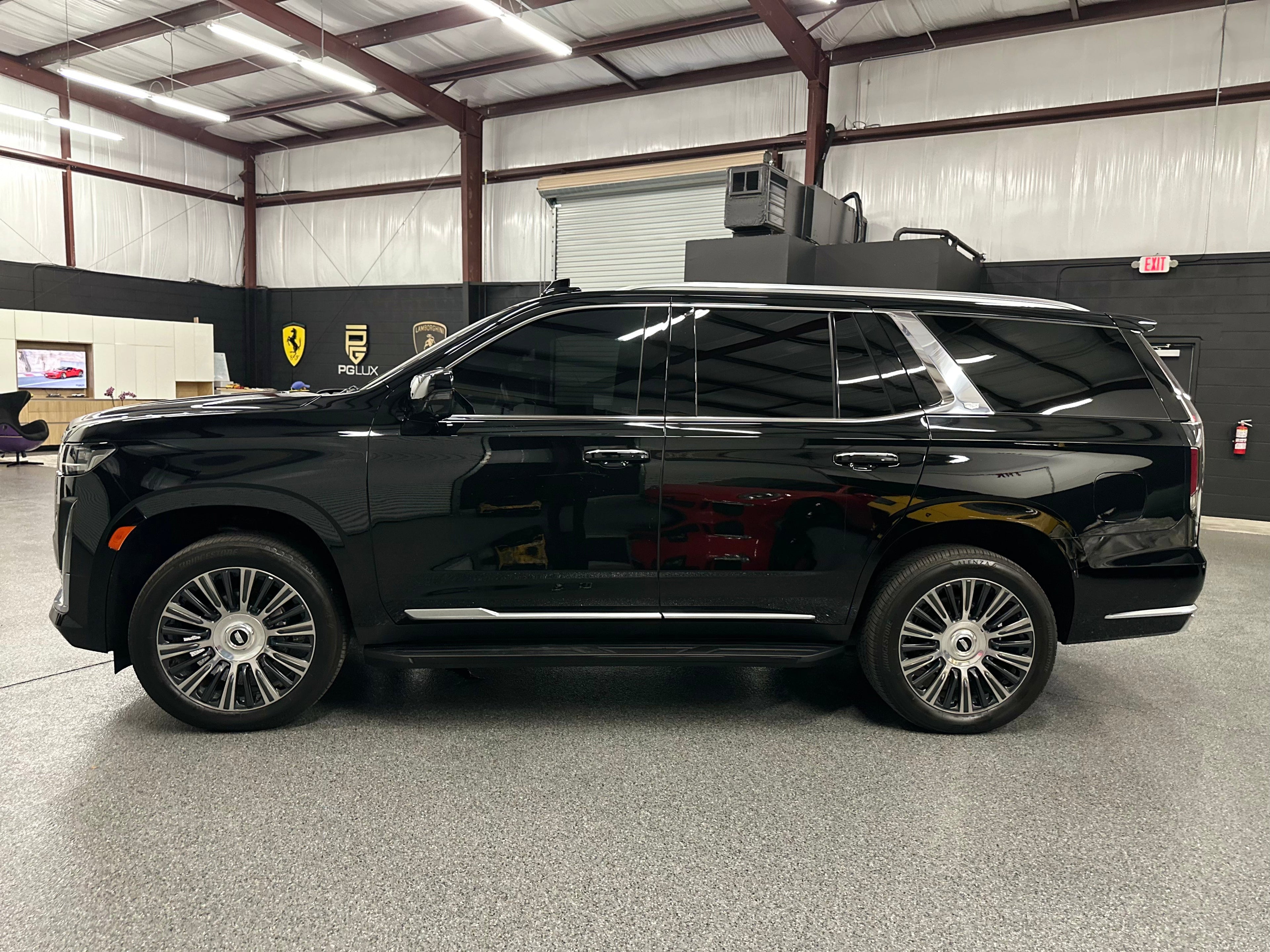 Black luxury full-size SUV with tinted windows and alloy wheels parked inside a showroom, premium family vehicle, modern spacious design.