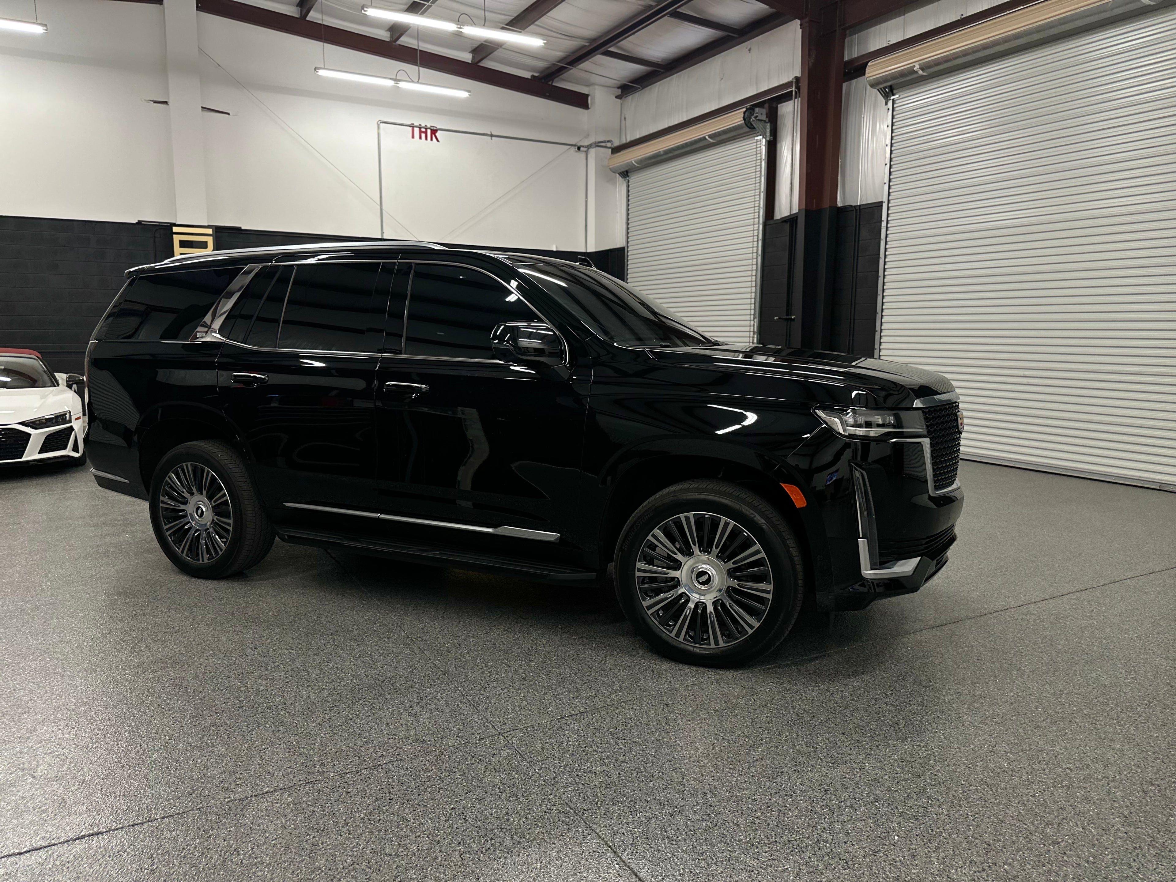 Black luxury full-size SUV with tinted windows and stylish alloy wheels parked in an indoor garage, premium family vehicle with modern design.