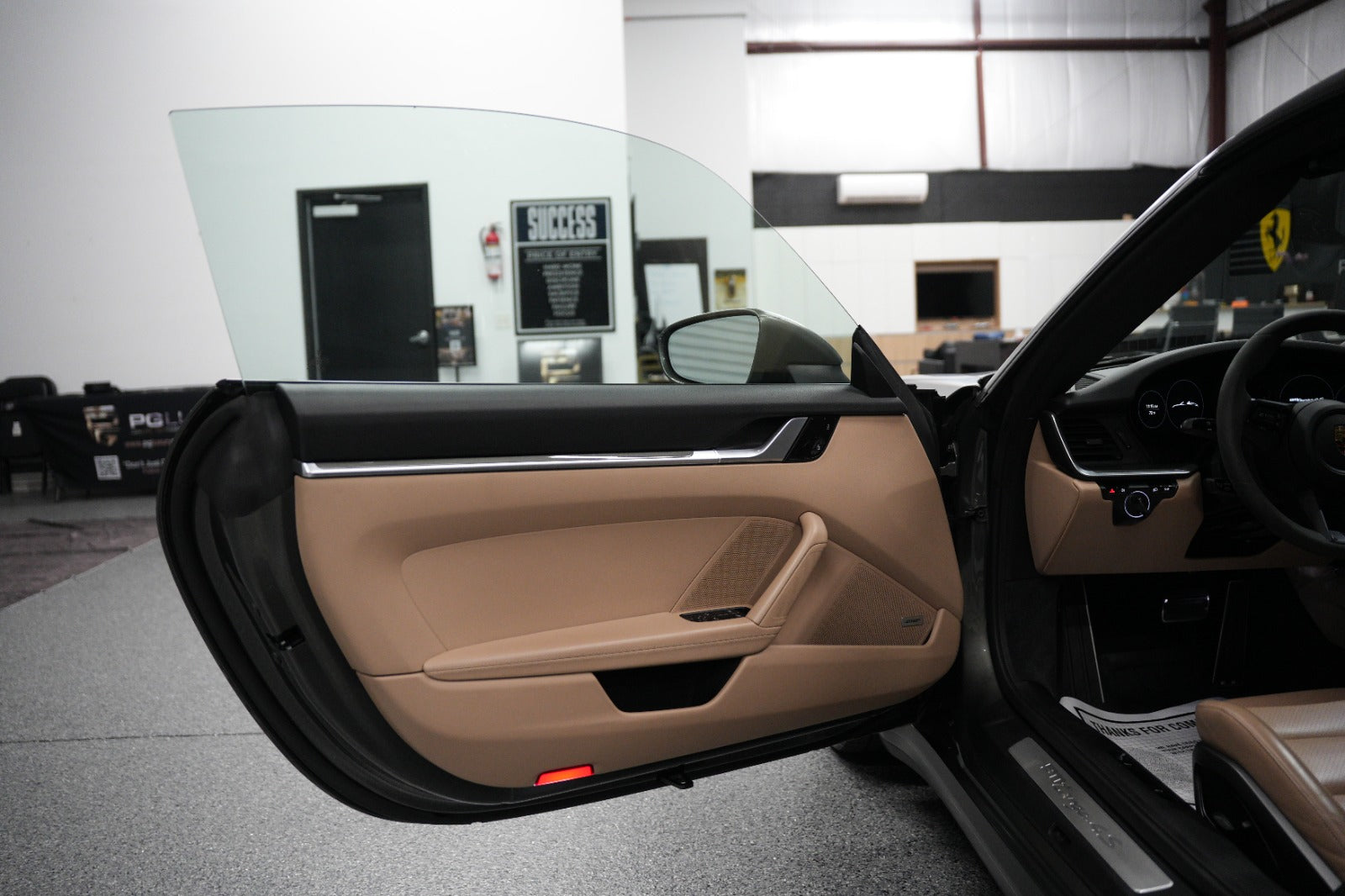 Beige leather car door interior panel with black trim and chrome accent, featuring power window controls and side mirror, luxury sports car door design.