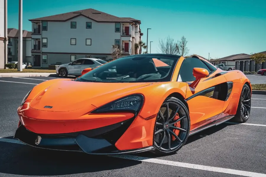 Orange sports car on a street with buildings in the background