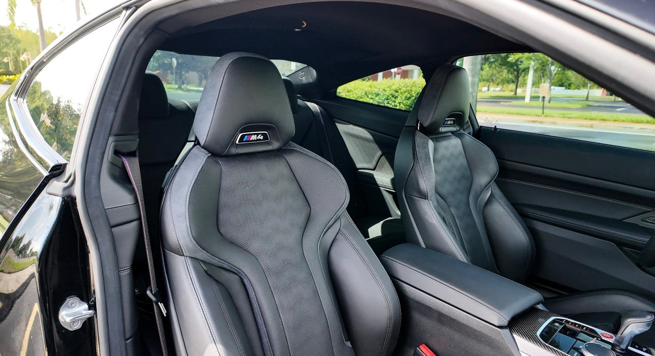Premium black leather BMW M4 sports car seats with ergonomic design and M4 logo, showcasing luxury interior and advanced comfort features.