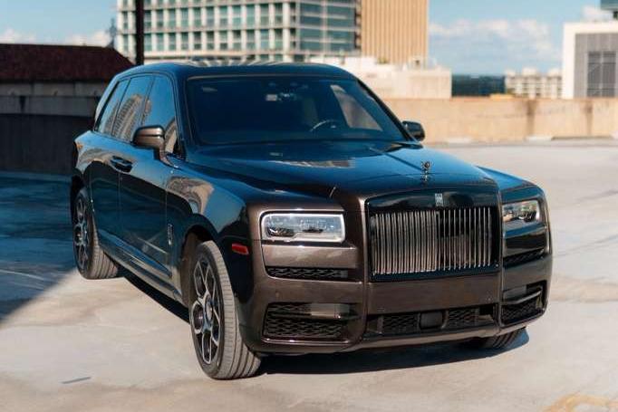 Luxury black Rolls-Royce Cullinan SUV parked on rooftop, premium luxury car with sleek design and iconic grille, high-end performance vehicle.