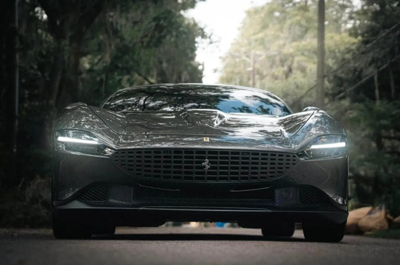 Sleek black Ferrari luxury sports car front view with LED headlights, aerodynamic design, and iconic prancing horse emblem.