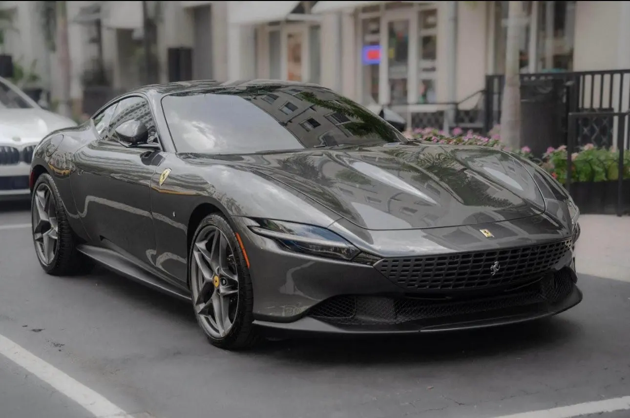 Sleek dark gray Ferrari Roma luxury sports car parked on city street, high-performance Italian coupe with aerodynamic design and stylish alloy wheels.