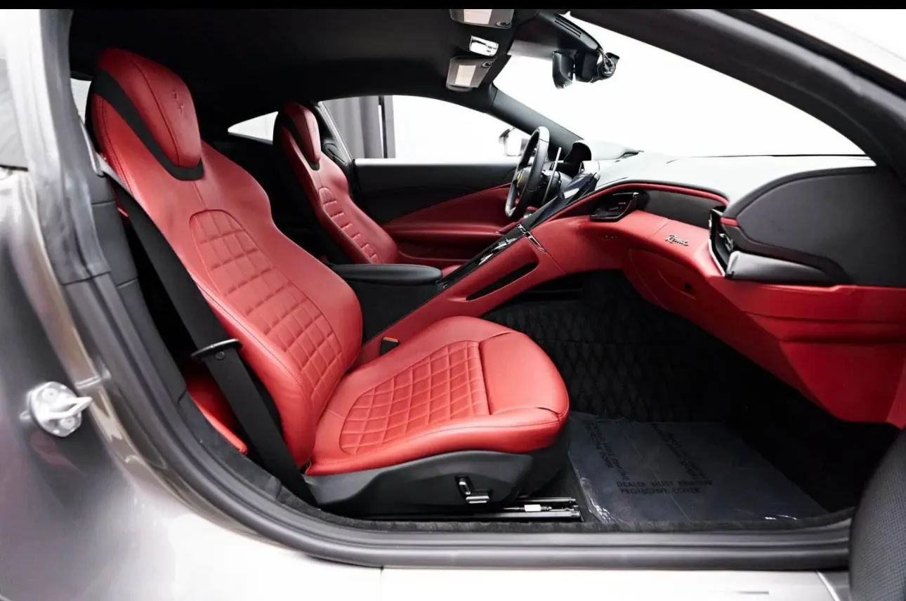 Luxury sports car interior featuring premium red leather seats with quilted stitching, ergonomic design, and advanced dashboard controls in a high-performance vehicle.