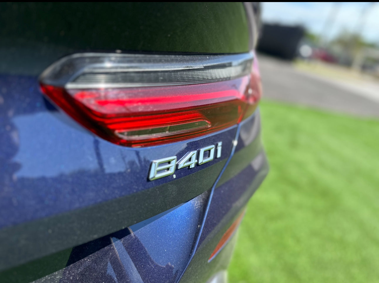 Close-up of blue BMW 840i rear with LED tail light and model badge, luxury sports car exterior detail.