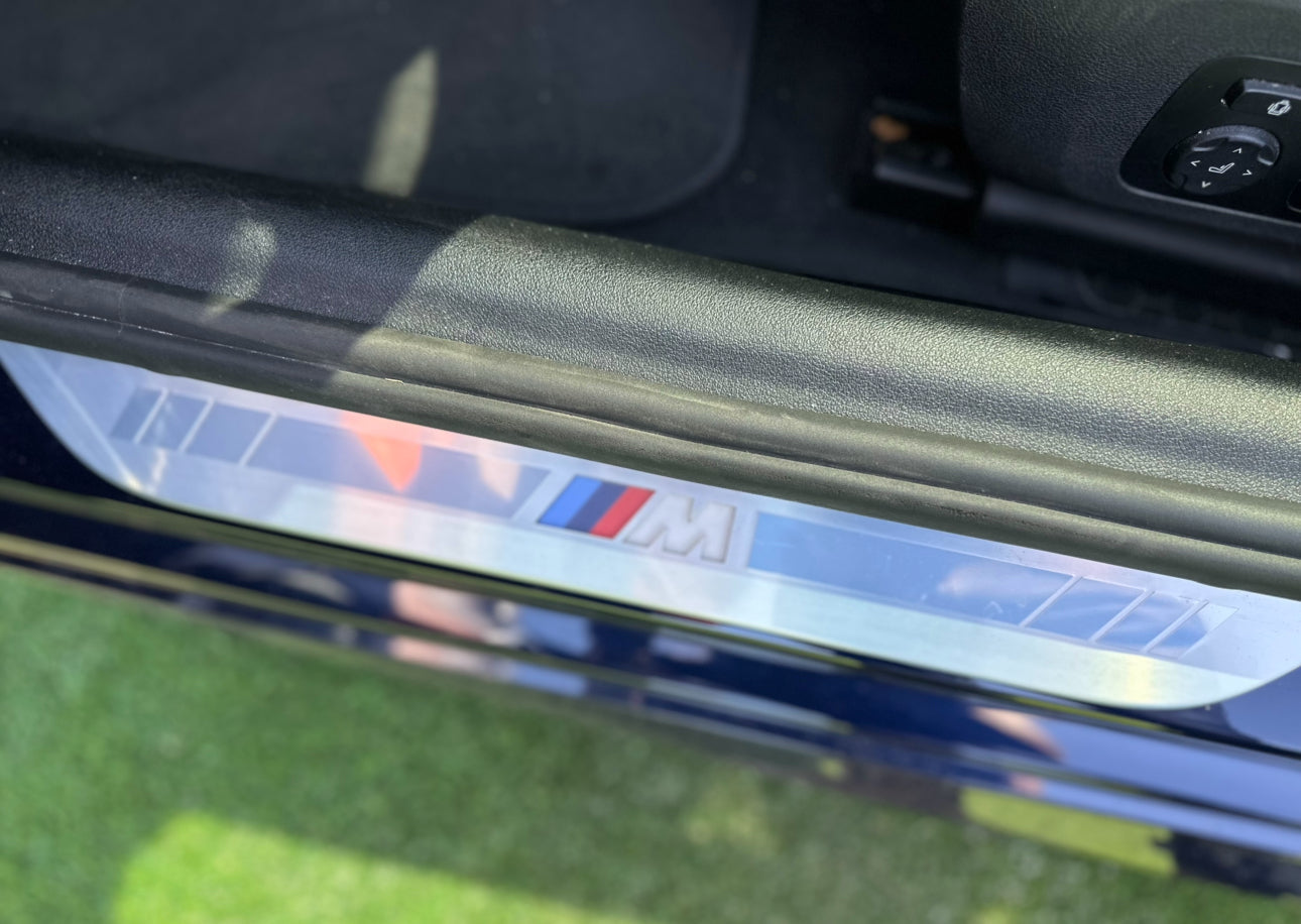 BMW M car door sill protector with brushed aluminum finish and M logo trim detail for luxury vehicle accessories.