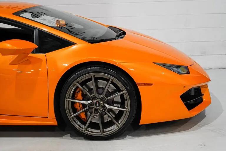 Close-up of vibrant orange sports car front side featuring sleek aerodynamic design, alloy wheel with high-performance brake caliper, and LED headlight, perfect for luxury car enthusiasts.