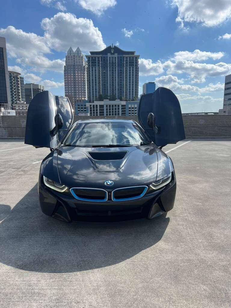 BMW i8 with futuristic scissor doors in downtown Orlando, showcasing luxury car rental experience.