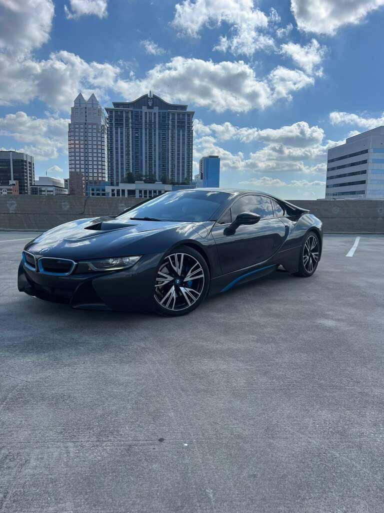 BMW i8 luxury car rental in Orlando with futuristic design and stunning skyline in the background.