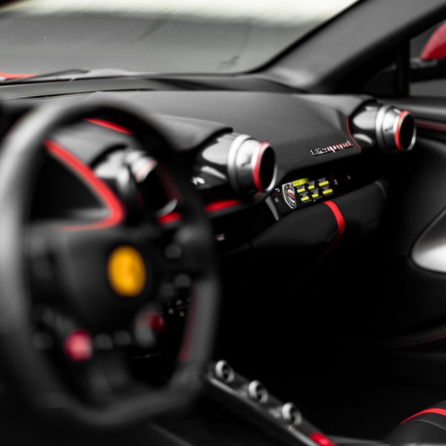 Luxury sports car interior with black leather dashboard, red contrast stitching, and advanced digital display panel.