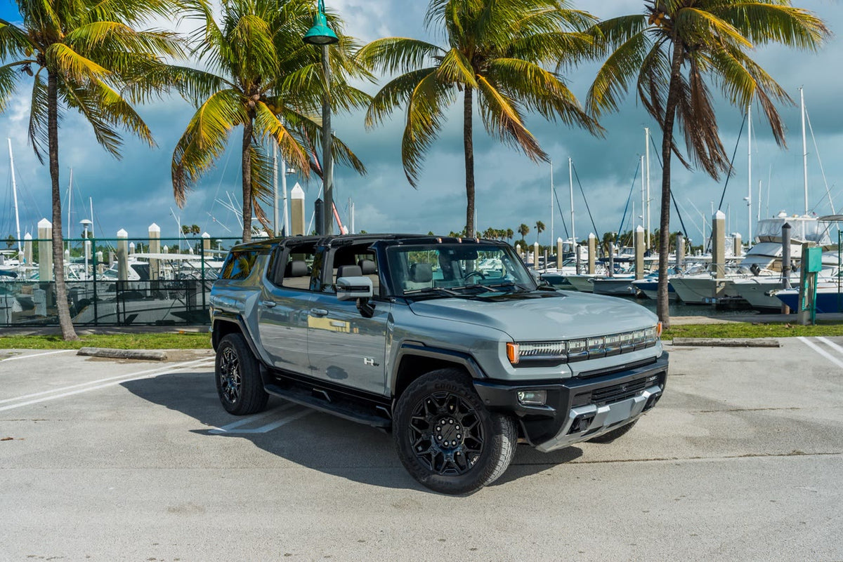 GMC Hummer EV SUV parked under palm trees by the water