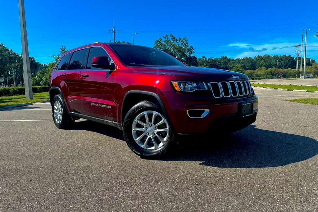 Red Jeep SUV parked on a paved surface with a clear blue sky