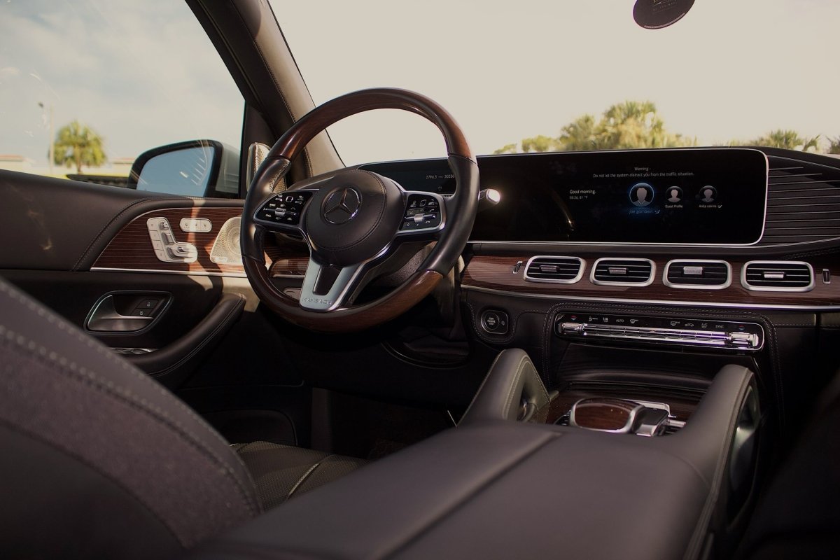 Luxury Mercedes Maybach car interior with leather seats, wood trim steering wheel, and advanced digital dashboard display